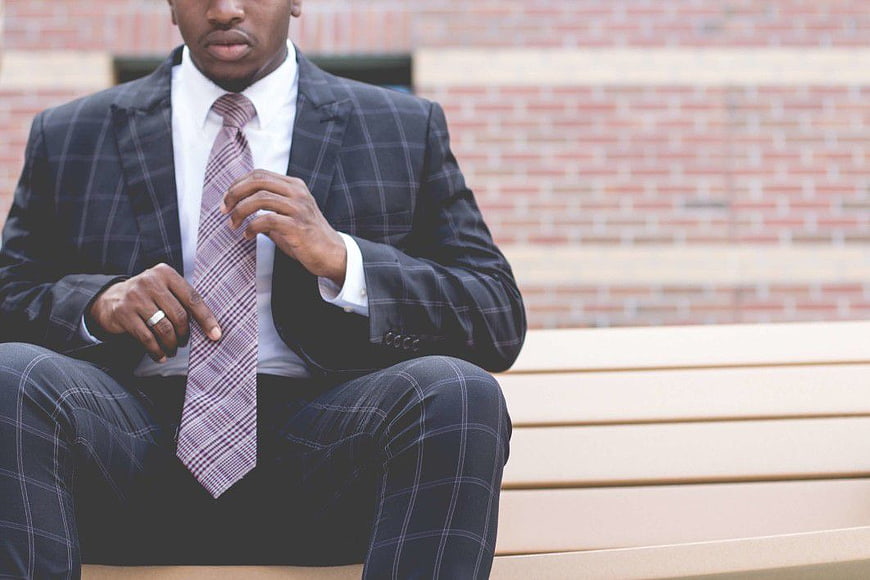 Man in Plaid Suit Adjusting Tie on Bench