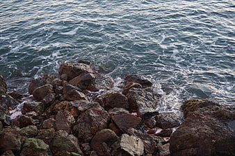 Rough ocean waves crashing against dark rocky shoreline