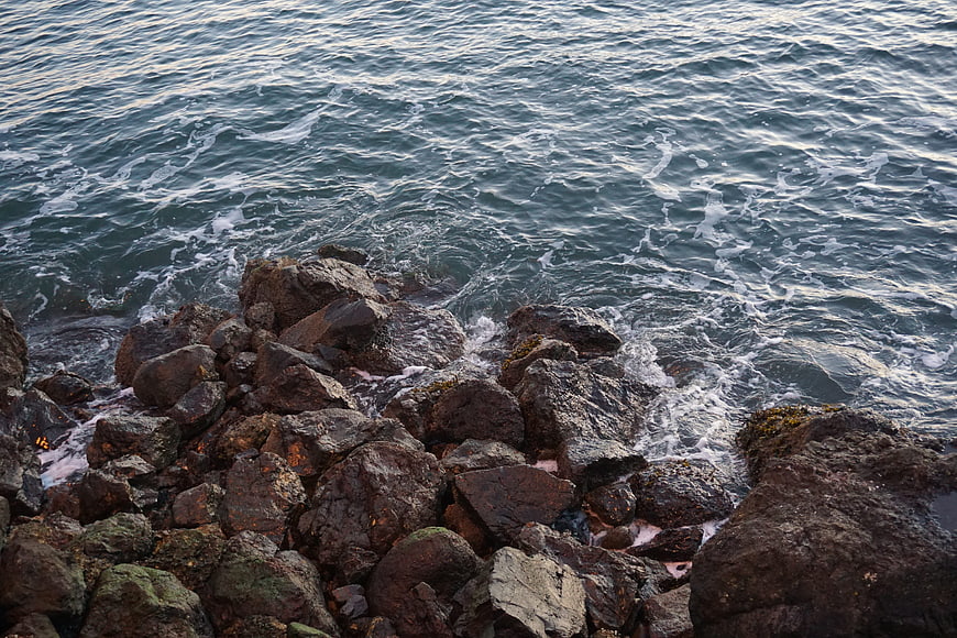 Rough ocean waves crashing against dark rocky shoreline