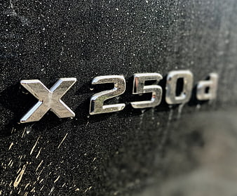 Close-up of Mercedes-Benz X250d emblem on dirty black car