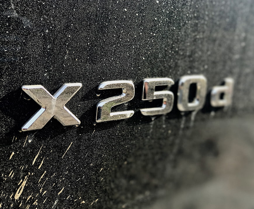 Close-up of Mercedes-Benz X250d emblem on dirty black car