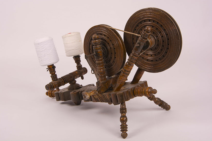 Antique wooden spinning wheel with white thread spools