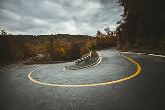 Winding Mountain Road with Autumn Foliage and Overcast Sky