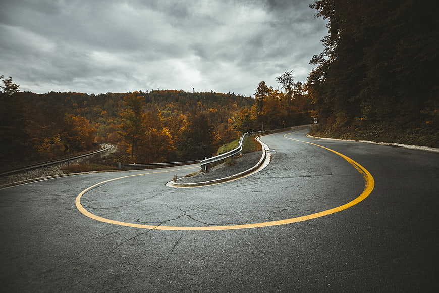 Winding Mountain Road with Autumn Foliage and Overcast Sky