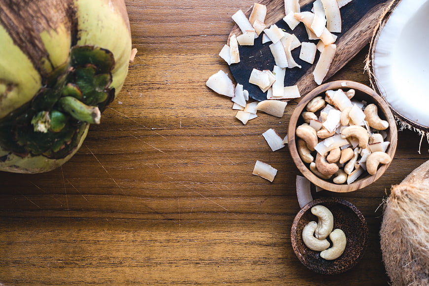 Top view of cashew nuts and coconut on a wooden table