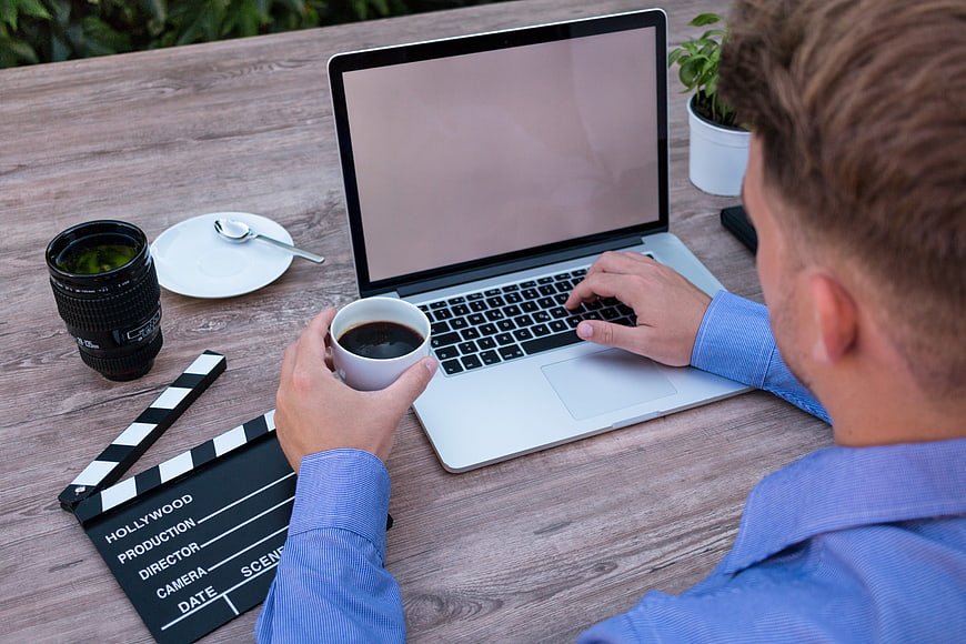 Filmmaker working on laptop with clapperboard and coffee