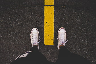Top View of White Sneakers on Asphalt Road with Yellow Line