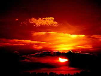Dramatic fiery red sunset with clouds and silhouette