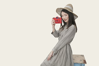 Asian woman with straw hat holding red camera