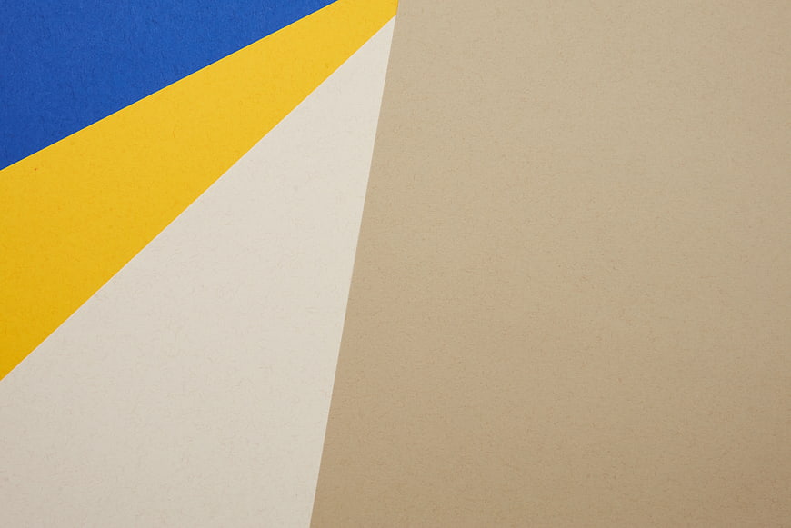 Abstract geometric paper background with blue, yellow, and beige sections