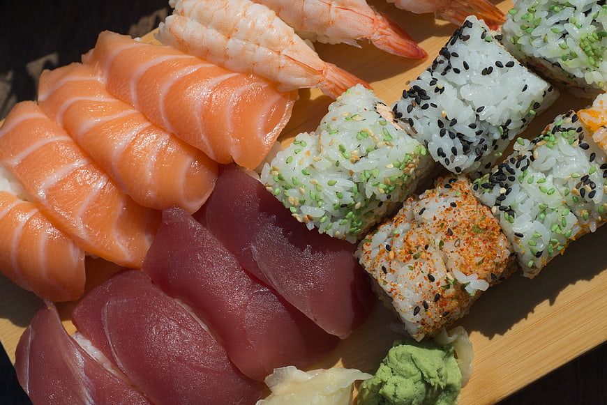 Assorted sushi platter with salmon, tuna, and rolls on wooden board