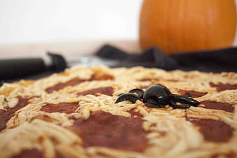 Close-up of Halloween pizza with olive spider and pumpkin