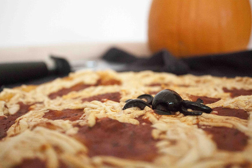 Close-up of Halloween pizza with olive spider and pumpkin