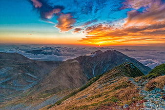 Dramatic Sunset Over Mountain Peaks Above Sea of Clouds