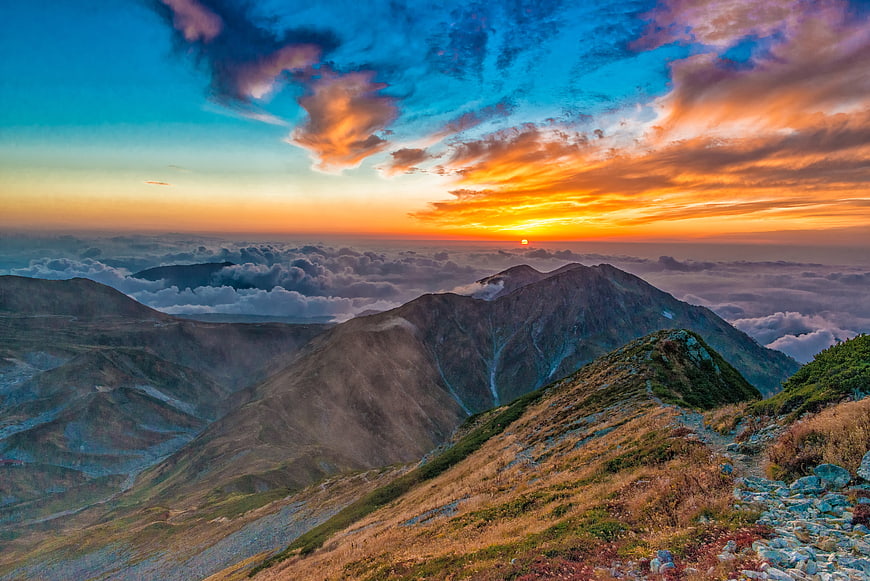 Dramatic Sunset Over Mountain Peaks Above Sea of Clouds