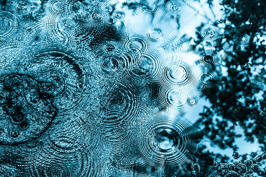 Blue Raindrops Creating Ripples in a Puddle