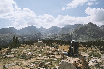 Hiker with backpack sitting on rock overlooking mountain range