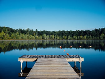 Serene Wooden Dock on Calm Lake with Forest Reflection