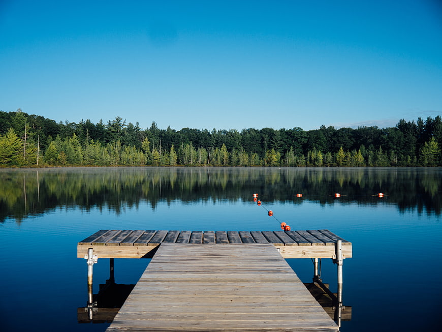 Serene Wooden Dock on Calm Lake with Forest Reflection