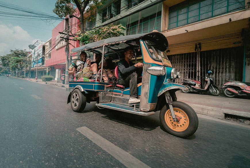 Colorful Tuk-Tuk Driving on Thai Street with Happy Passengers