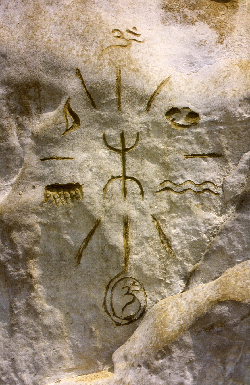 Ancient spiritual symbols and Om engraved on textured sandstone rock surface