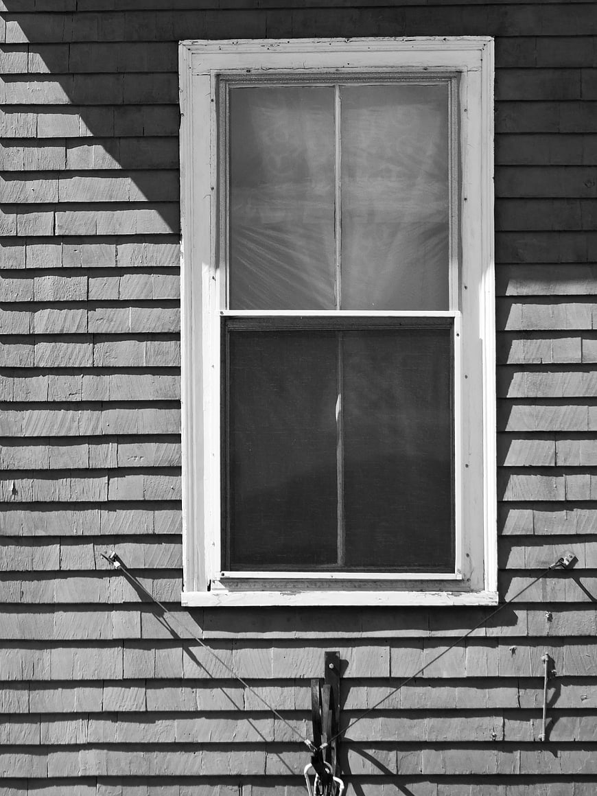 Black and white photo of old window on wooden siding