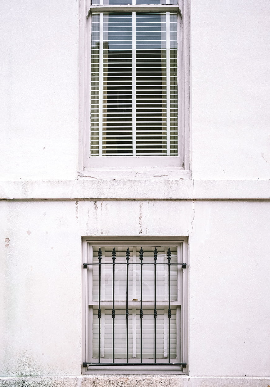 Minimalist White Building Facade With Two Windows And Iron Grille