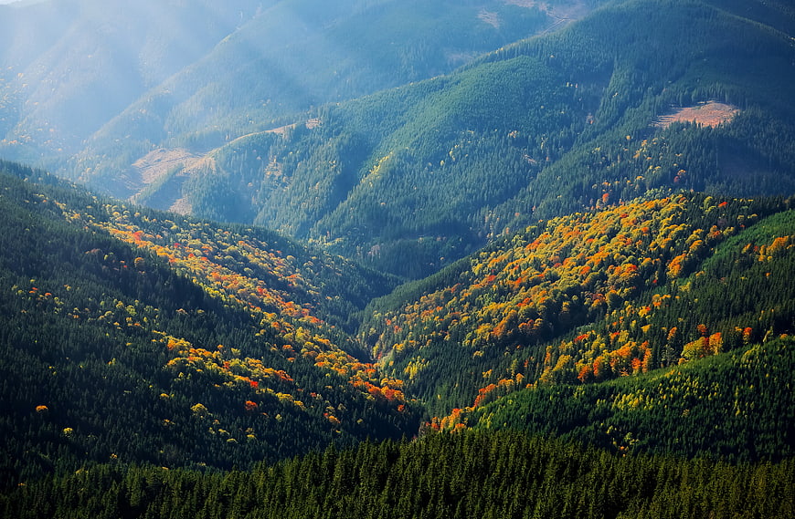 Aerial View of Mountain Valley with Autumn Foliage and Sunbeams