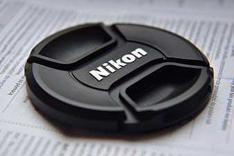 Close-up of Nikon camera lens cap on document