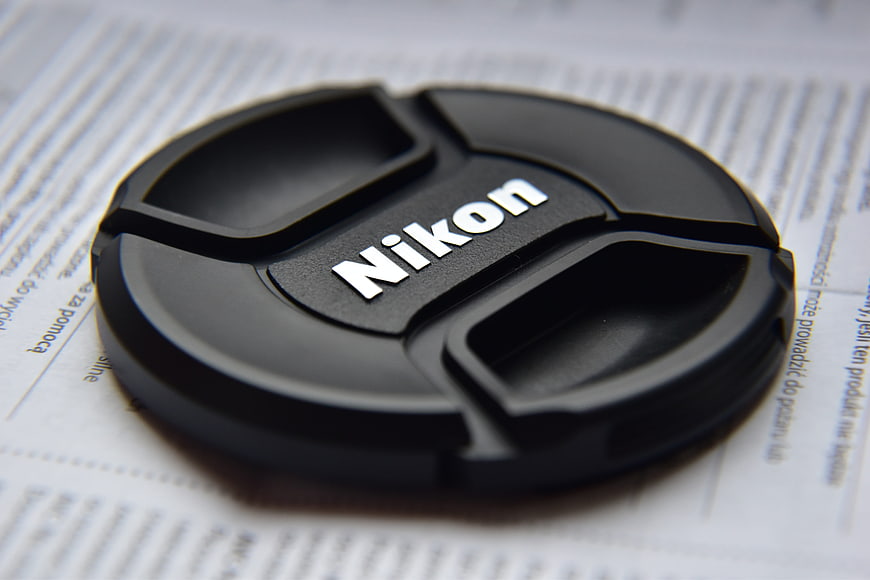Close-up of Nikon camera lens cap on document
