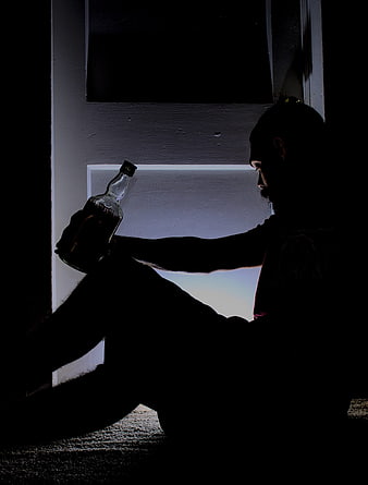Silhouette of Man Sitting Alone with Alcohol Bottle