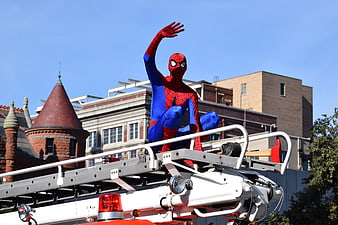 Spider-Man Figure Waving From Fire Truck Ladder In Urban Setting