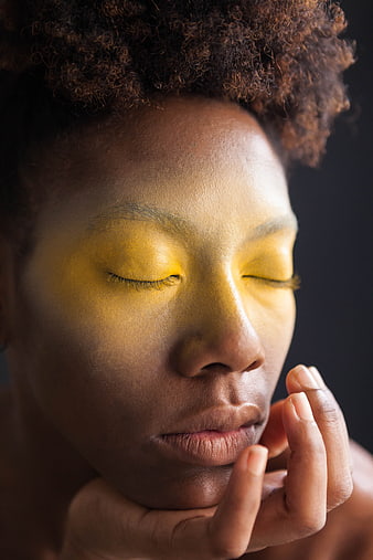 Close-up portrait of woman with yellow light on closed eyes