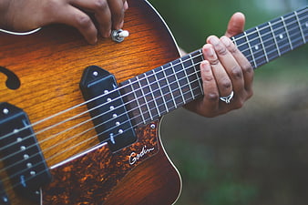 Close-up of hands playing a Godin acoustic-electric guitar