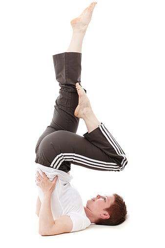 Woman performing advanced yoga headstand pose on white background