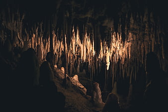 Dark Cave Interior with Illuminated Stalactites and Stalagmites