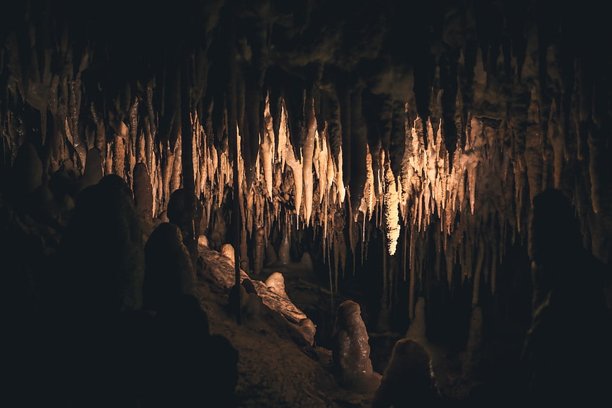 Dark Cave Interior with Illuminated Stalactites and Stalagmites