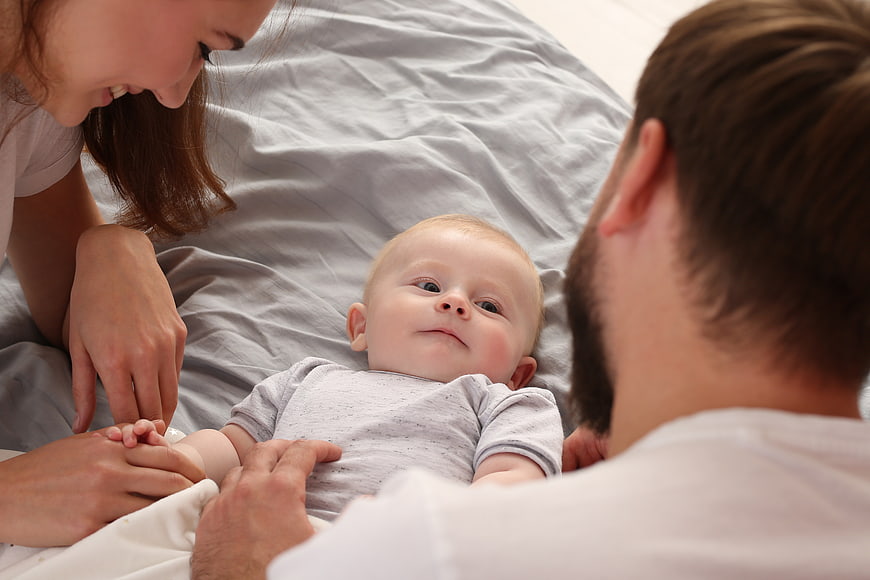 Happy Parents Playing with Baby on Bed