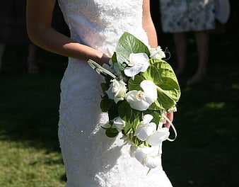 Bride holding white orchid bouquet in lace wedding dress