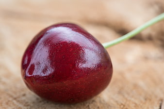 Close-up of a single fresh red cherry on wood