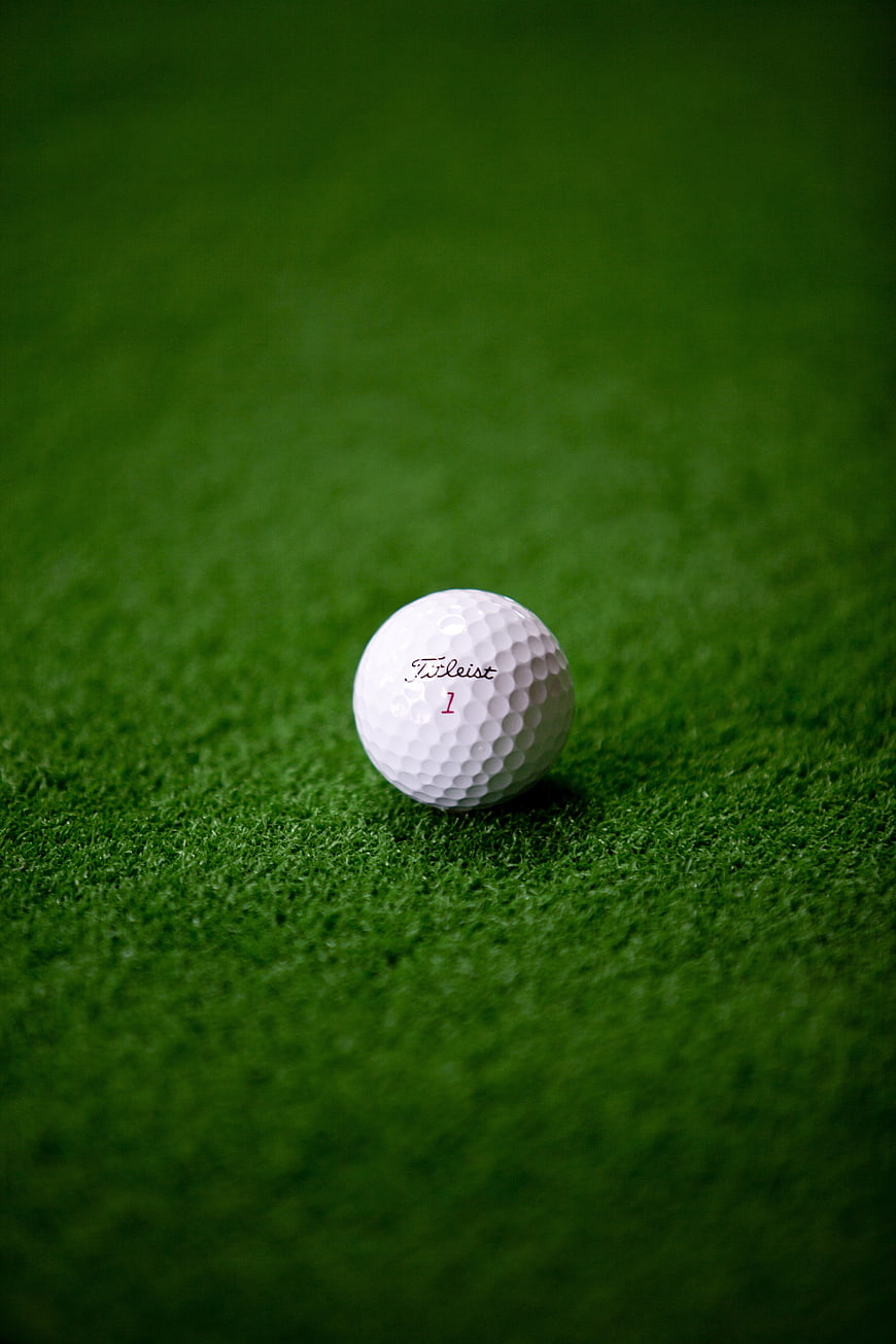 White golf ball on green grass with shallow depth of field