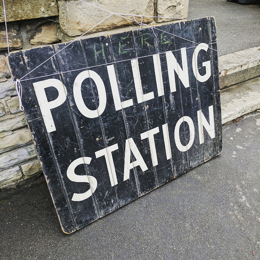 Vintage Wooden Polling Station Sign on Stone Wall