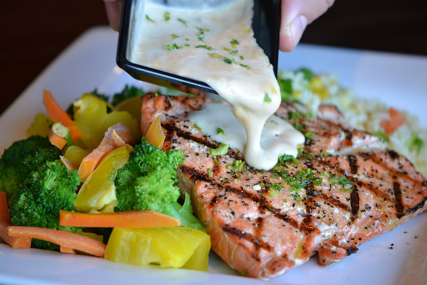 Grilled salmon fillet with creamy sauce and vegetables