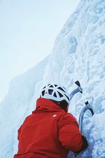 Ice Climber in Red Jacket Scaling Frozen Waterfall