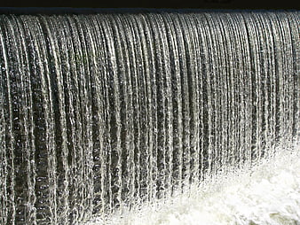 Close-Up Vertical Water Cascade Flowing Over Textured Sluice Surface