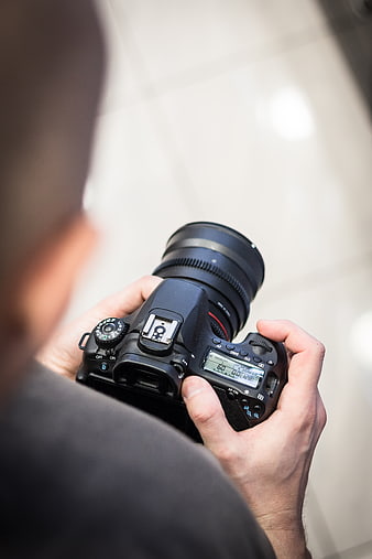 Over-the-shoulder view of photographer holding DSLR camera