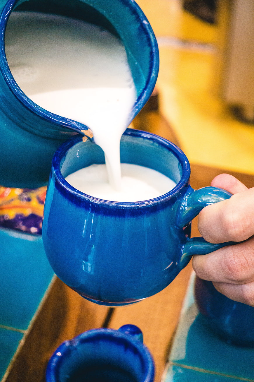 Pouring traditional Iranian yogurt drink Doogh into blue ceramic mug
