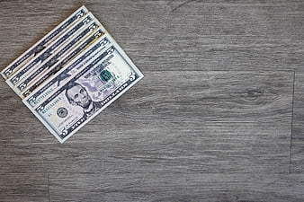 Stack of five dollar bills on gray wooden background