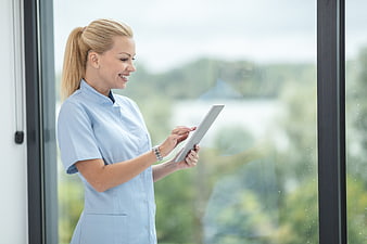 Smiling female nurse using tablet in hospital window