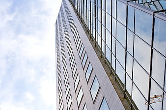 Low angle view of modern glass skyscraper against blue sky